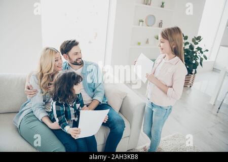 Big adopted family diligent student little girl presenting parents best exam mark full of pride Stock Photo