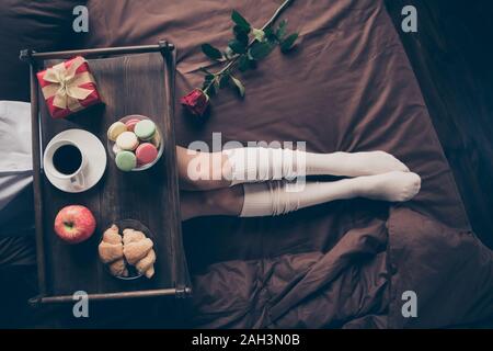 Cropped top above high angle view of nice attractive girl lying on bed long legs enjoying romance occasion event fresh delicious snack on sheets linen Stock Photo