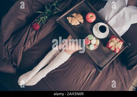 Cropped top above high angle view of nice attractive girl sitting on bed long legs wearing gaiters enjoying romance occasion event fresh snack on Stock Photo