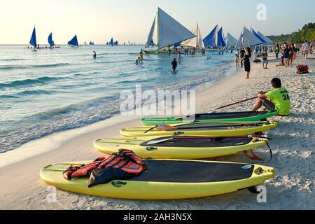 Boracay, Aklan Province, Philippines - January 13, 2019: Sunset at the White Beach with paddle boards and sailing boats waiting for tourists Stock Photo