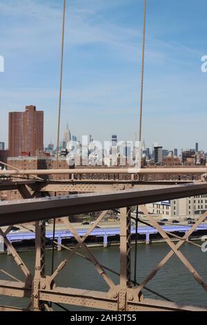 Detail of the Brooklyn Bridge with the view of Manhattans skyline and the Empire State Building in the distance. New York City, New York State, USA. Stock Photo