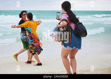 Boracay, Aklan Province, Philippines - December 3, 2019: A woman making a photo from two asian women in colorful dresses dancing at the White Beach Stock Photo