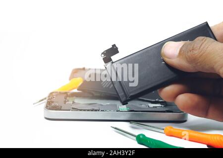 Phone repairs install battery into the motherboard for smartphone By technician on studio white background With mini tools Stock Photo