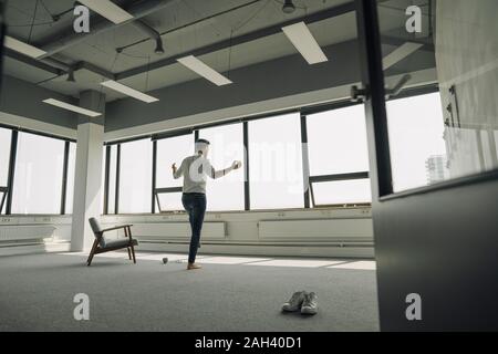 Mature businessman practicing yoga in empty office Stock Photo