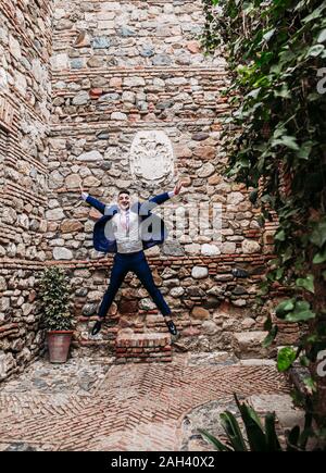 Excited elegant man jumping at an old building Stock Photo