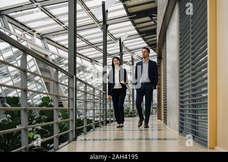 Businessman and businesswoman walking in modern office building Stock Photo