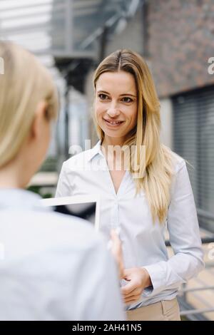 Portrait of young businesswoman smiling at colleague in office Stock Photo