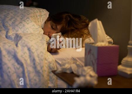 Sick woman using tissues in the bed