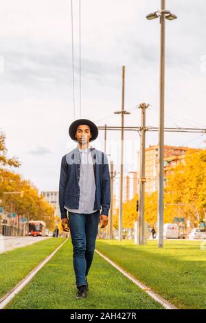 Fashionable young man walking on tram rails Stock Photo