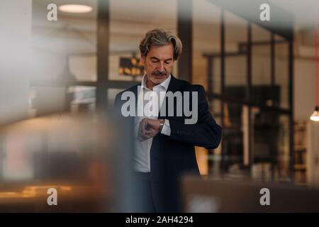 Senior businessman checking the time in office Stock Photo