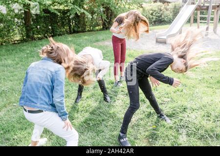 Four girls shaking their heads covered with dandelion seeds Stock Photo