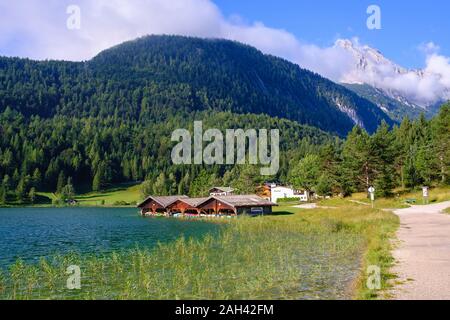 Germany, Bavaria, Mittenwald, Lakeshore boathouses with forested Wetterstein Mountains in background Stock Photo