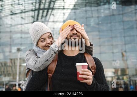 Happy young woman surprising boyfriend at the central station, Berlin, Germany Stock Photo