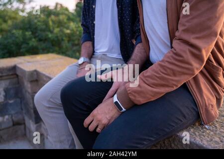 Close-up of affectionate gay couple sitting on a wall Stock Photo