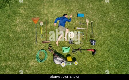 View from above of a gardener in laying on the grass with all the tools he need for take care of garden Stock Photo