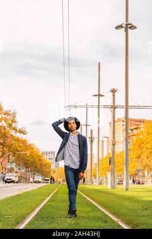 Fashionable young man walking on tram rails Stock Photo