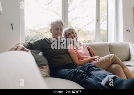 Portrait of senior couple relaxing on couch at home Stock Photo