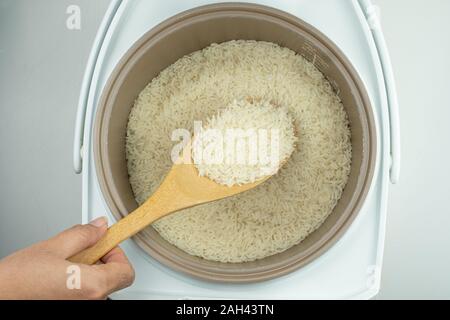 wood ladle at rice and the electric rice cooker on white background Stock Photo