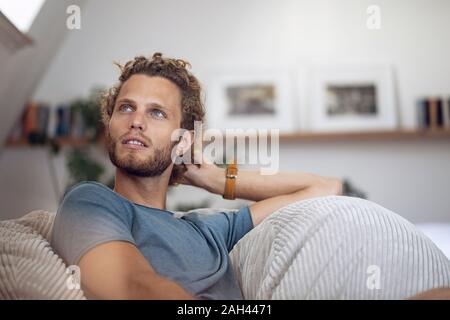 Young man relaxing in beanbag at home Stock Photo