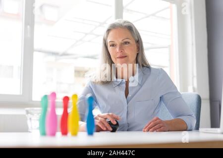 Mature businesswoman playing with pins on desk in office Stock Photo