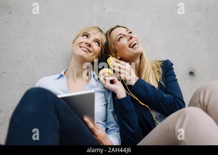 Two happy young businesswomen sharing headphones Stock Photo