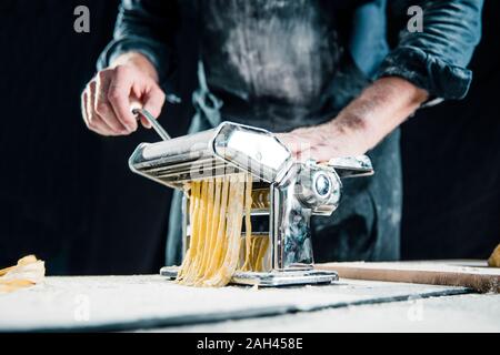 Hobby chef making fresh tagliatelle with pasta machine Stock Photo