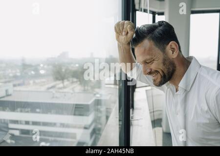 Mature businessman looking out of window in office Stock Photo