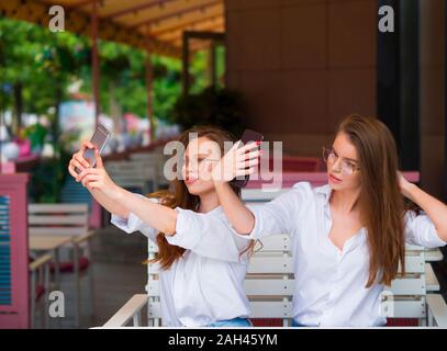 Two women makeing a selfie while sitting in a summer cafe. Meeting and friendship. Social networks concept Stock Photo