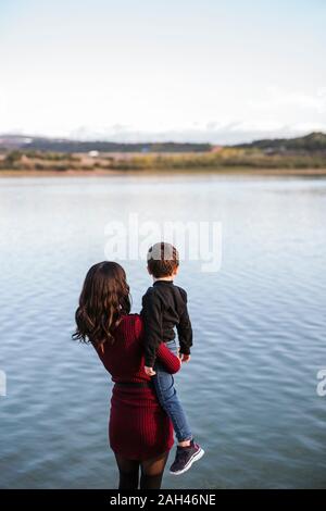 Mother and son looking at lake, rear view