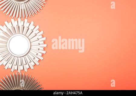 Mirrors in the shape of the sun with metallic golden frames with rays on a bright pink background with copy space. Stock Photo