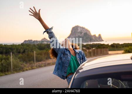 Young woman during road trip with raised arm Stock Photo