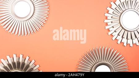 Mirrors in the shape of the sun with metallic golden frames with rays on a bright pink background with copy space. Stock Photo