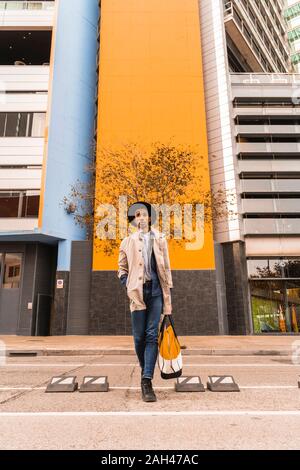 Young man wearing a hat and carrying a bag outdoors Stock Photo
