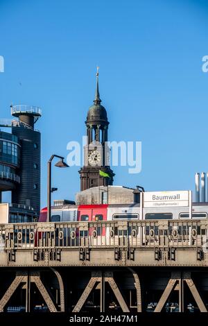 Germany, Hamburg, Elevated train with Saint Michaels Church bell tower in background Stock Photo
