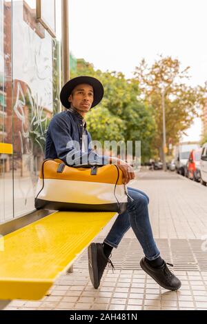 Young man wearing a hat and carrying a bag outdoors Stock Photo