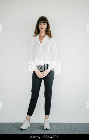 Smiling businesswoman standing in front of a white wall Stock Photo