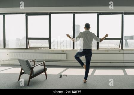 Mature businessman practicing yoga in empty office Stock Photo