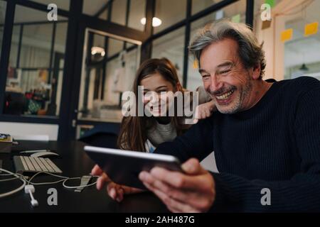 Happy casual senior buisinessman and girl using tablet in office Stock Photo