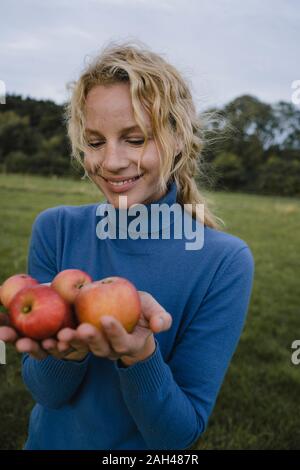 Smiling young woman holding apples in the countryside Stock Photo