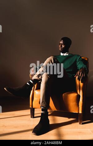 Man sitting in leather armchair looking sideways Stock Photo