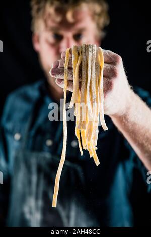 Hobby chef holding fresh tagliatelle pasta Stock Photo