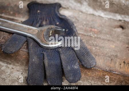 Close-up used wrench. Chrome-plated open-end wrench on a work glove. Auto repair shop. Without people. Soft focus. Stock Photo