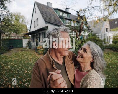 Happy senior couple in garden of their home in autumn Stock Photo