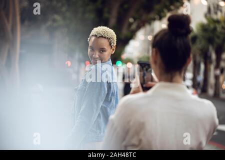 Young woman posing for a smartphone picture in the city Stock Photo