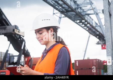 Female worker with clipboard taking notes on industrial site Stock Photo