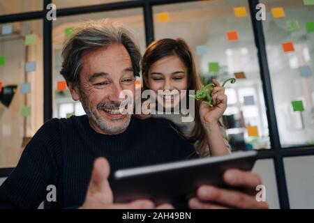 Happy casual senior buisinessman and girl using tablet in office Stock Photo