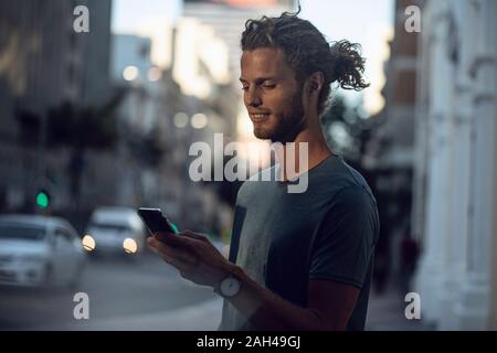 Confident young man using smartphone in the city Stock Photo