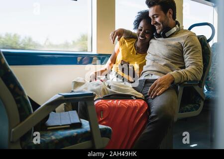 Young couple with smartphone relaxing in a train Stock Photo