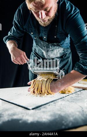 Hobby chef making fresh tagliatelle with pasta machine Stock Photo