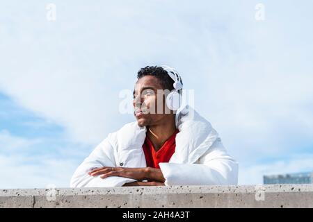 Young man listening to music with headphones outdoors Stock Photo
